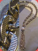 Long chain necklace, golden tone with faux pearl and chans as pendant. Probably 80's.